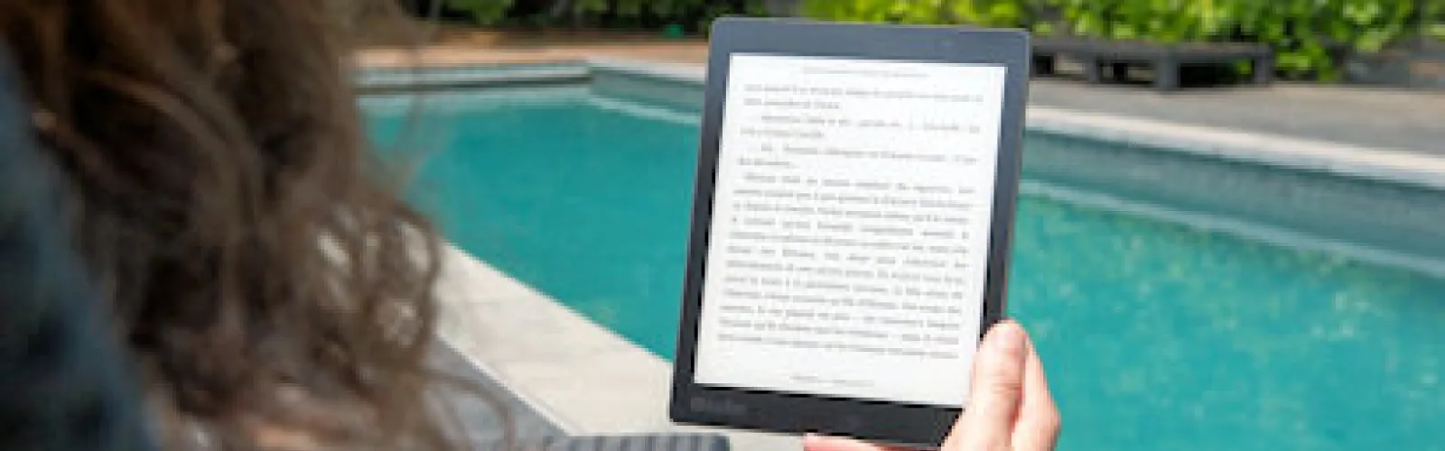 Woman reading an ebook by a pool